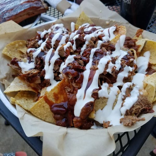 Doc's Smokehouse BBQ nachos with pulled pork, barbecue sauce, and white drizzle.